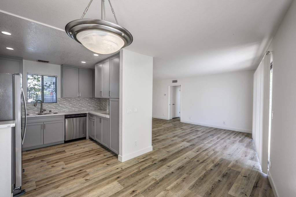 A spacious kitchen with wood floors and sleek gray cabinets, perfect for those seeking apartments for rent in Sherman Oaks.